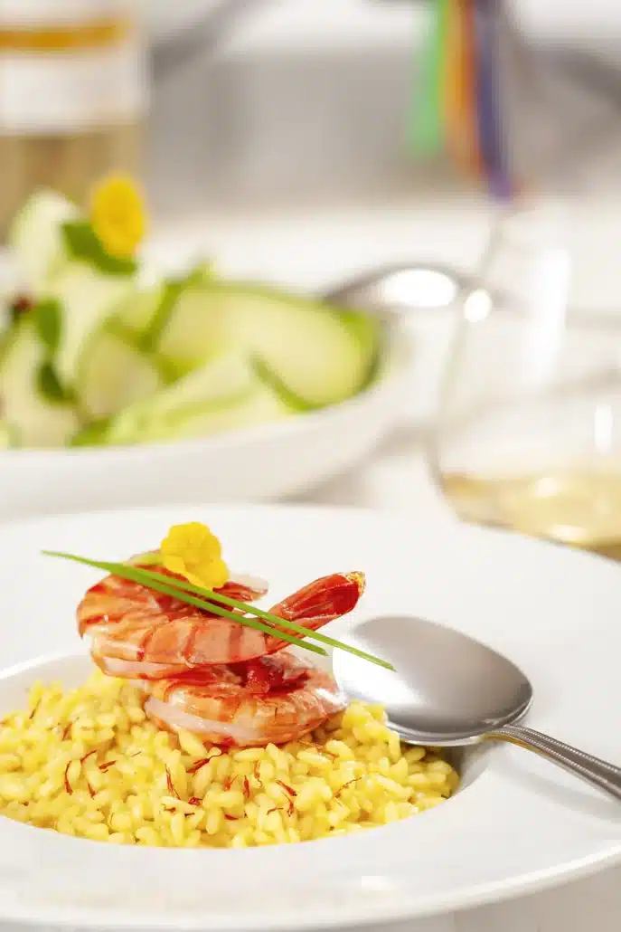 Italiaanse Risotto met saffraan en garnalen met bloem op een wit bord.