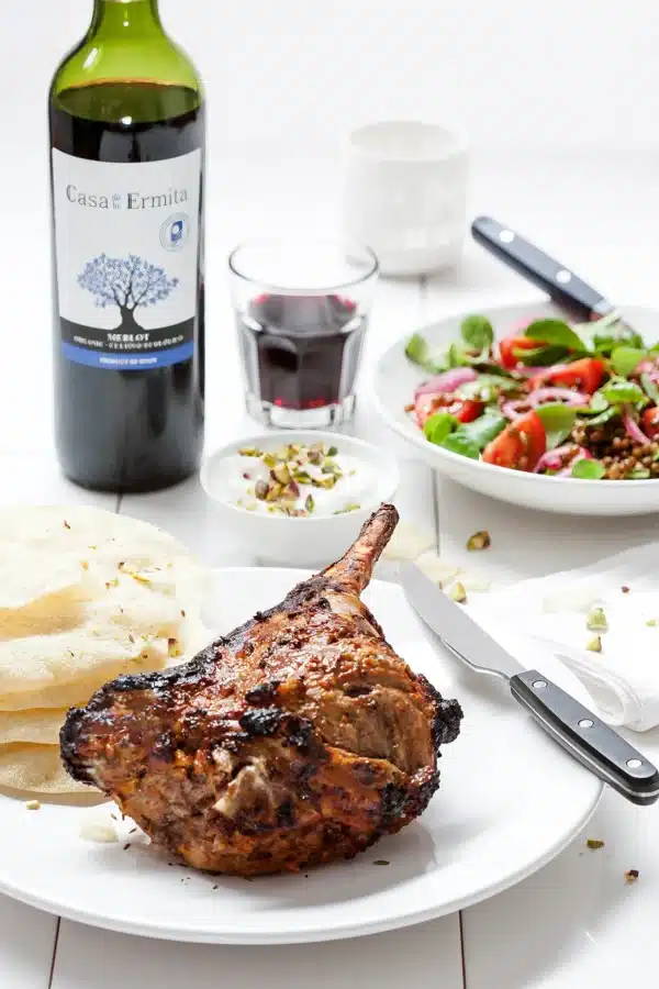 lamsbout uit de oven met linzensalade en papadums met glas roode wijn