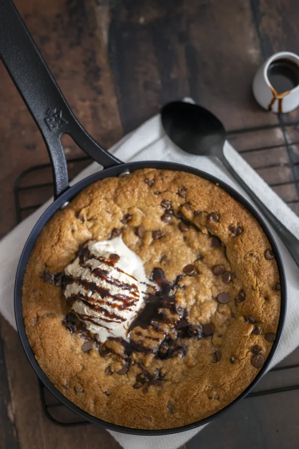 Giant chocolate chip pan cookie in een zwarte skillet met vanille-ijs en chocoladesaus