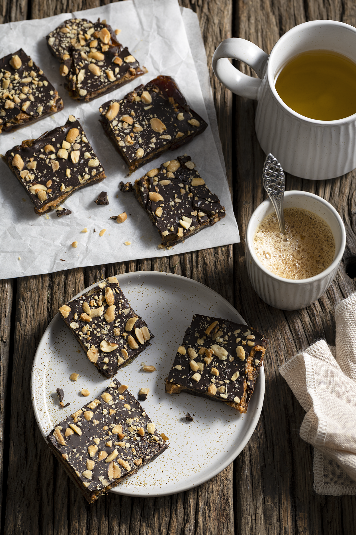 Gezonde chocolade dadel repen met pindakaas geserveerd met koffie en thee op houten tafel