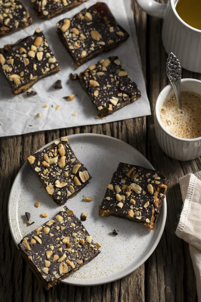 Chocolade dadel reep met pindakaas en gehakte pinda’s close-up op bord, gezonde snack zonder bakken