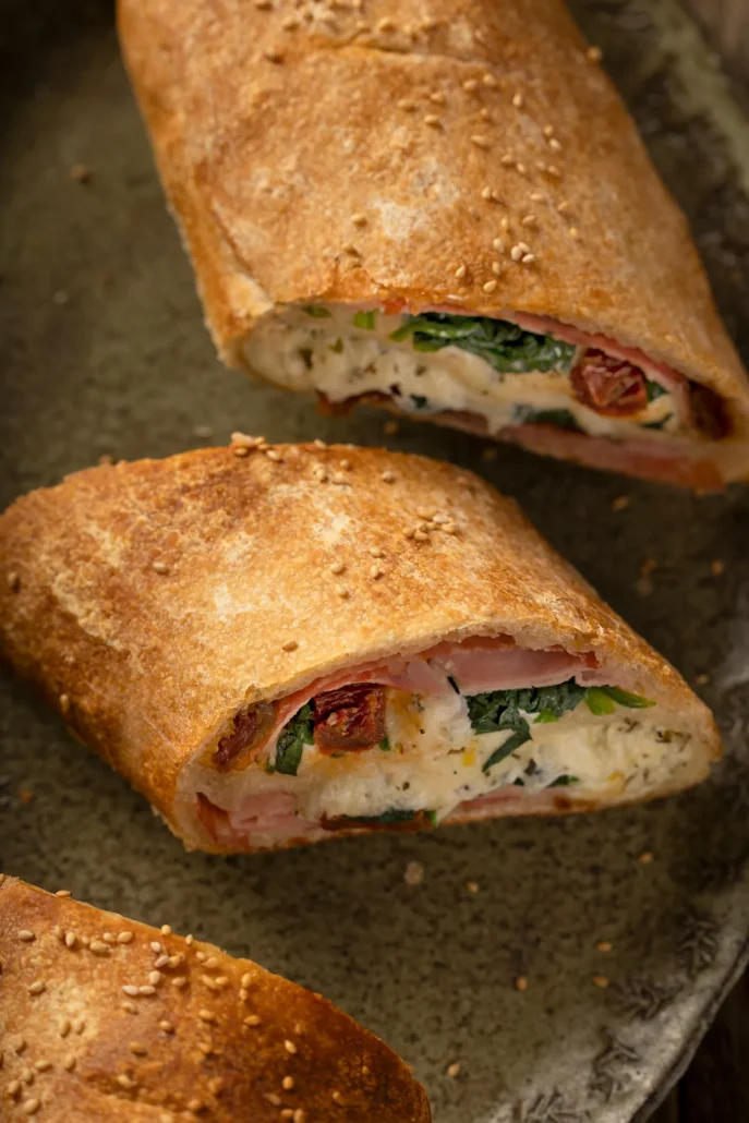 Close up van stromboli met romige ricotta vulling, spinazie en zongedroogde tomaat