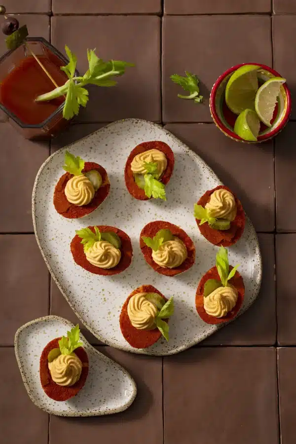 Overzicht van gevulde eieren Bloody Mary met paprikapoeder, augurk en selderij op een serveerschaal