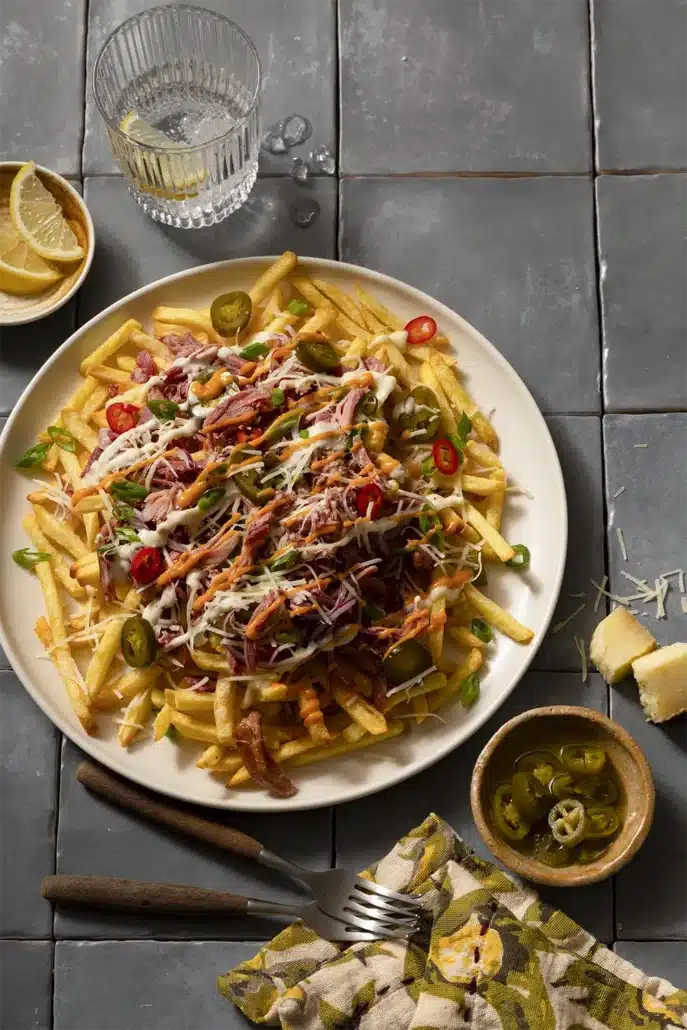 Loaded fries met pulled pork, jalapeño, kaas, lente-ui, truffelmayonaise en Sriracha mayo met citroen en extra jalapeño erbij